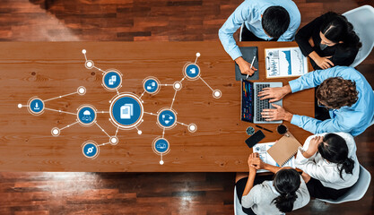 A diverse team engaged in a collaborative management meeting, utilizing technology for data analysis and project planning in a modern workspace. Amity