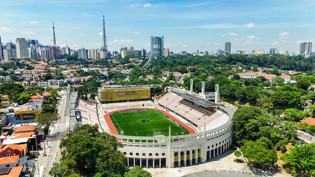 Imagem a&eacute;rea do Est&aacute;dio do Pacaembu integrado ao cen&aacute;rio urbano de S&atilde;o Paulo, revelando contraste entre arquitetura esportiva, &aacute;reas verdes e a metr&oacute;pole ao redor. S&atilde;o Paulo SP em 29 dez 2025