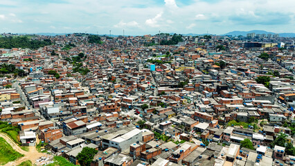 Imagem a&eacute;rea de comunidade urbana com alta densidade de constru&ccedil;&otilde;es, representando ocupa&ccedil;&atilde;o do solo, realidade social e desafios da urbaniza&ccedil;&atilde;o.