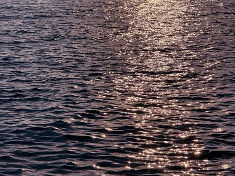 Dark twinkling sea rippling water at night.