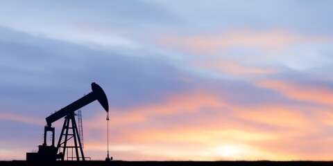 Black and white image of a pump jack with a sunset in the background