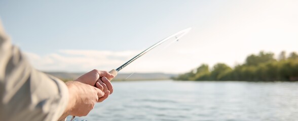 Man is holding a fishing rod and is fishing in a lake