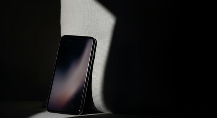 Smartphone on a stand, illuminated screen displaying a gradient, against a dark background with subtle shadows and contrast