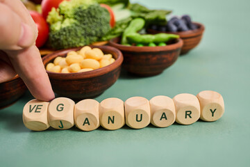 Hand arranging veganuary wooden cubes with healthy vegetables