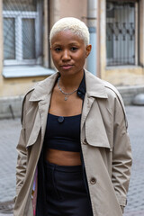 African American woman with short blond hair, wearing a beige coat, smiles. lady model is stylist for clothes and hair. young beautiful African woman is smiling.