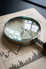 Magnifying glass scrutinizing financial stock market graph for investment analysis