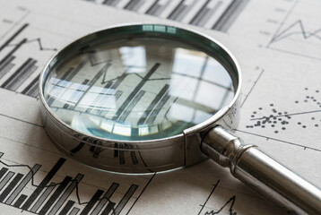 Glass lens magnifying complex business data charts during corporate audit
