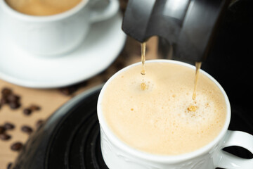Process of making coffee using a pod machine with two streams of beverage. © Zarina Lukash