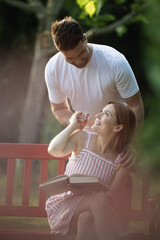 Couple in love, man suprising woman from behind in park
