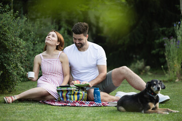 Couple having a picnic in park with their dog