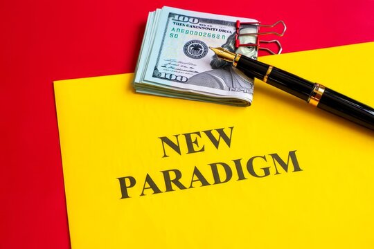 NEW PARADIGM word on a yellow piece of paper on dollars on a red background.