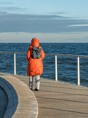 woman with backpack walking on pier