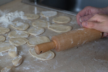 Hands of an older woman and child making dumplings together in a home kitchen. Warm family moment with homemade food, selective focus, and cozy cooking with grandma atmosphere.