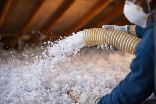 Worker Blowing Insulation Material into Attic During Home Energy Upgrade