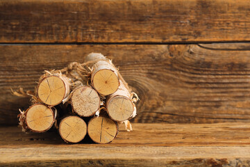 Stack of birch logs tied with rope on wooden background