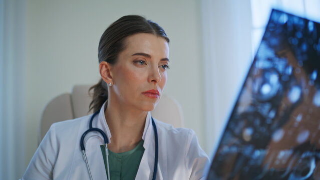 Doctor looking patient radiology scan closeup. Stressed woman feeling shocked