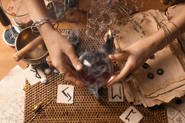 Fortune teller with crystal ball reading future  at table, top view