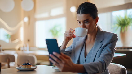 Business owner enjoying coffee looking smartphone modern city restaurant closeup