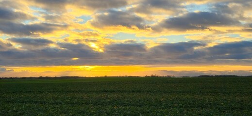 Sonnenuntergang &uuml;ber einem weiten Feld auf der Insel R&uuml;gen mit dramatischem Wolkenhimmel