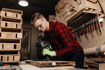 Young male carpenter working on a piece of wood in his workshop, focusing on craftsmanship and detail
