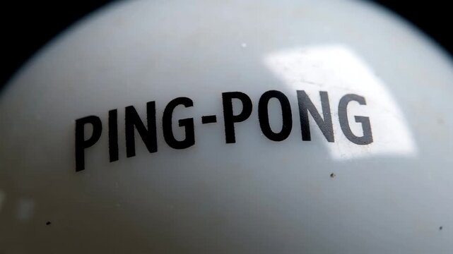 White plastic ping pong ball with black capital text macro shot in bright studio lighting