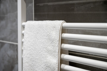 Warm towel hanging on a heated rack in a bathroom during the evening