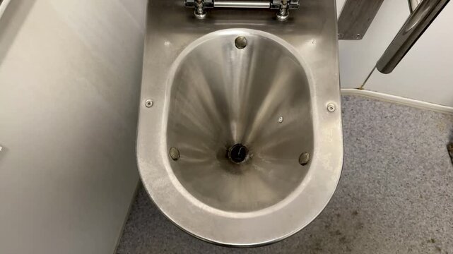 Stainless Toilet With Yellow Stain In Accessible Stall, Metal Commode And Handrail Visible, Compact Institutional Layout With NonSlip Flooring, Maintenance Inspector Plot Checking