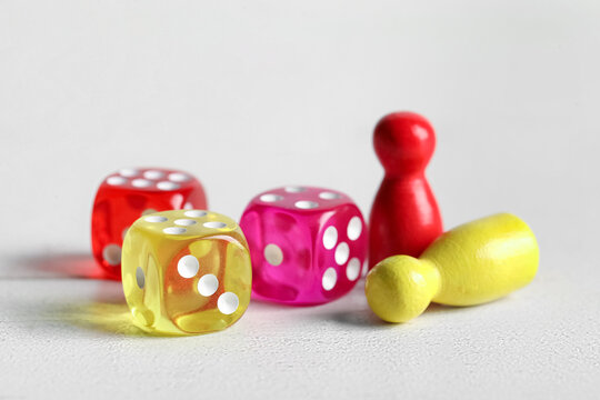Different game dices and pawns on white wooden background