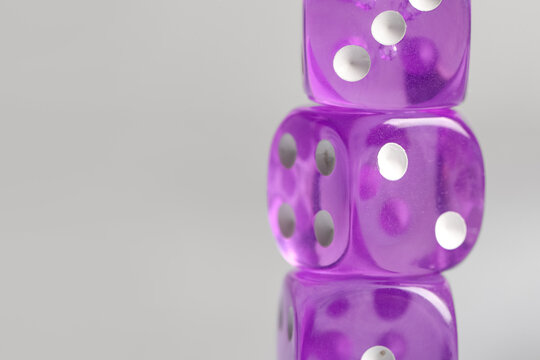 Purple game dices on grey background, closeup