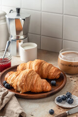 Delicious breakfast with croissants on wooden tray and coffee on white kitchen table background