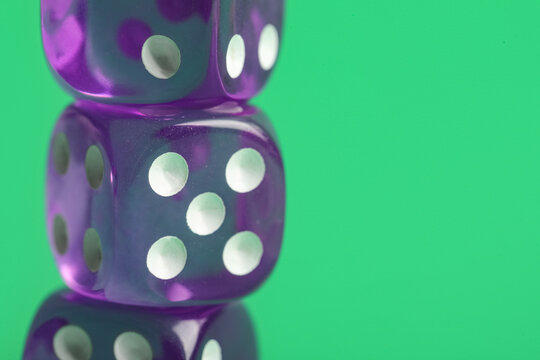 Purple game dices on green background, closeup