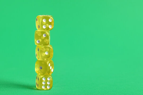 Stack of yellow game dices on green background