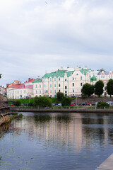 Calm Waters Mirror Colorful Architecture, Gentle Ripples Over Tranquil Waters Beneath Overcast Sky