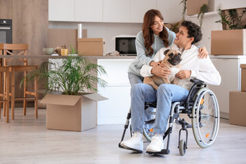 Young man in wheelchair with his girlfriend and dog on moving day