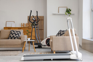 Interior of living room with sofas, elliptical machine and treadmill