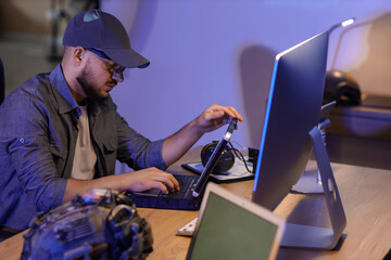 Young soldier working with military laptop on table in office at night