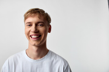 Smiling man wearing a plain white t shirt in a simple studio, conveying casual warmth, bright mood, friendly and approachable vibe suitable for lifestyle branding and positive messaging