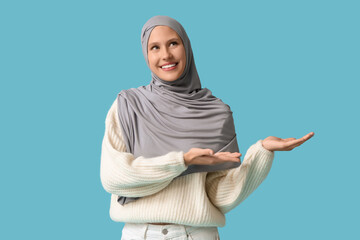 Young Muslim woman meditating on blue background
