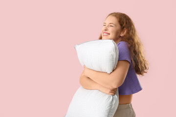 Happy young woman with white soft pillow on pink background