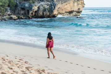 Woman walking on sandy beach next to ocean waves