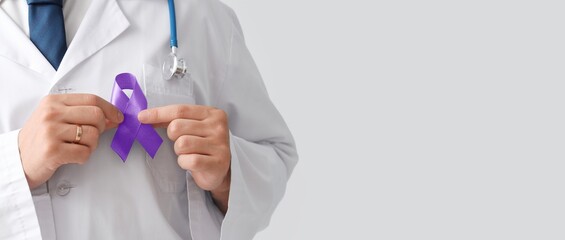 Doctor holding purple awareness ribbon on light background with space for text, closeup. World...