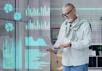 Mature programmer working with laptop near window in office