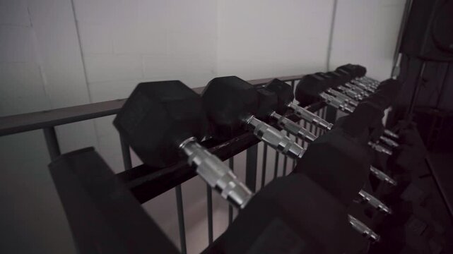 Row of hex dumbbells on a storage rack.