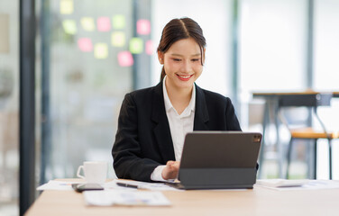 Fototapeta premium Asian Business woman using calculator and tablet laptop for doing math finance on an office desk, tax, report, accounting, statistics, and analytical research concept