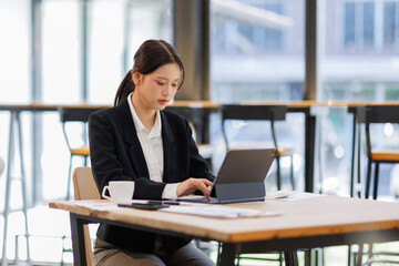 Asian Business woman using calculator and tablet laptop for doing math finance on an office desk, tax, report, accounting, statistics, and analytical research concept

