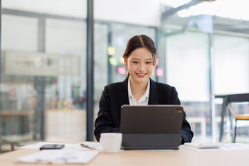 Fototapeta premium Asian Business woman using calculator and tablet laptop for doing math finance on an office desk, tax, report, accounting, statistics, and analytical research concept