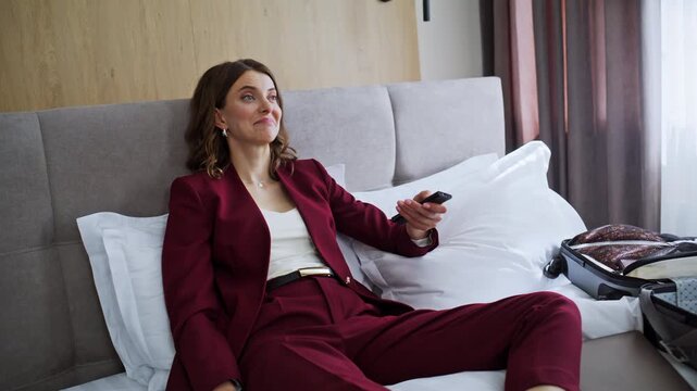 Smiling traveler watching TV in luxury hotel room closeup. Happy businesswoman