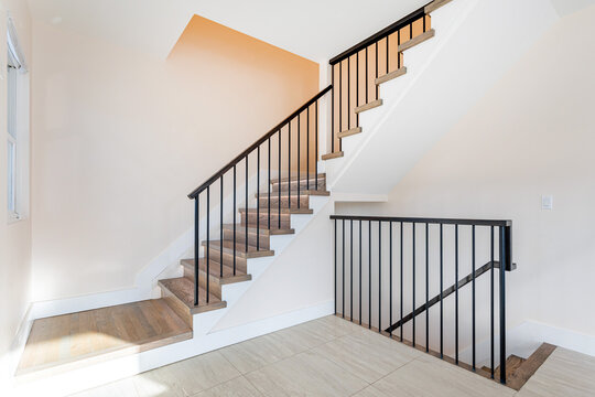 Modern interior staircase with wooden steps and black metal railing in bright minimalist home