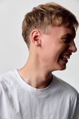 Naklejka premium Smiling man in a white t shirt is captured in a studio with a side profile, conveying casual happiness and relaxed mood suitable for lifestyle and fashion stock
