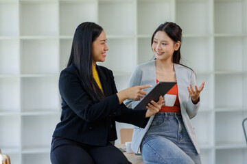 Fototapeta premium Two asian business are looking at a tablet screen planning analyzing real estate investment data report Financial and tax systems concept. 